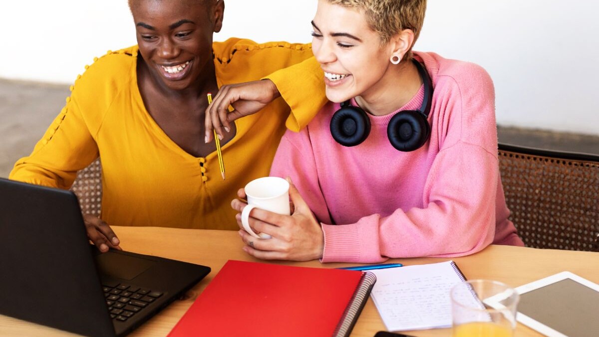 two queer women in front of laptop laughing